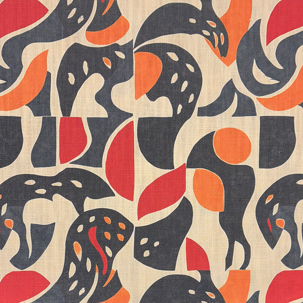 A bold designer upholstery fabric featuring fluid organic shapes in charcoal, red, and burnt orange on a neutral background.