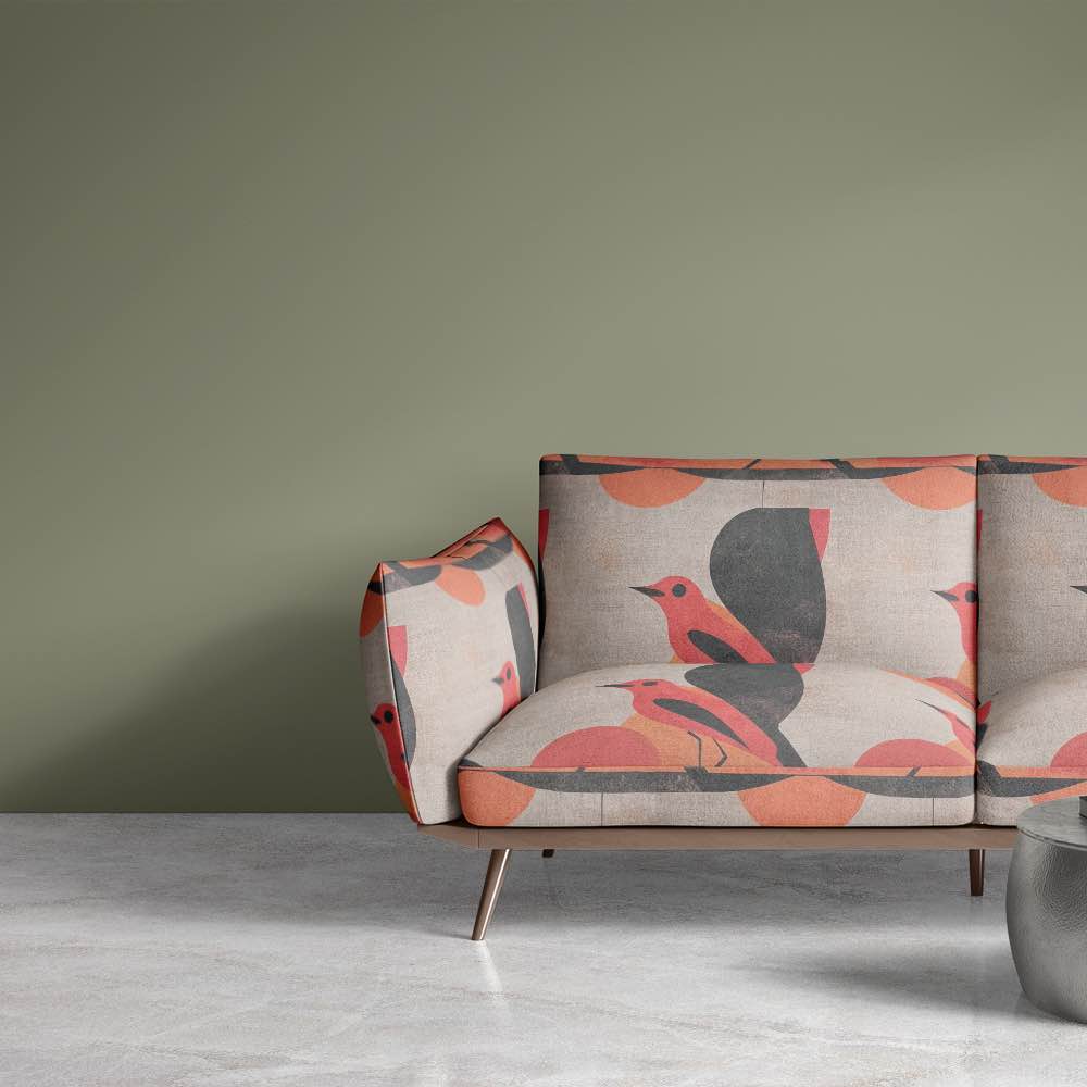 Bird No.15 luxury upholstery fabric in red and orange palette with abstract bird design on a sofa