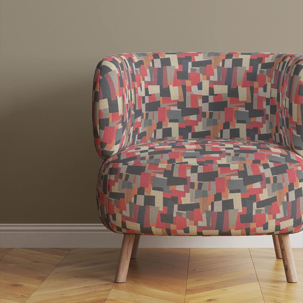 Chair view of Collage No.1 upholstery fabric in red, black, and grey with overlapping collage pattern