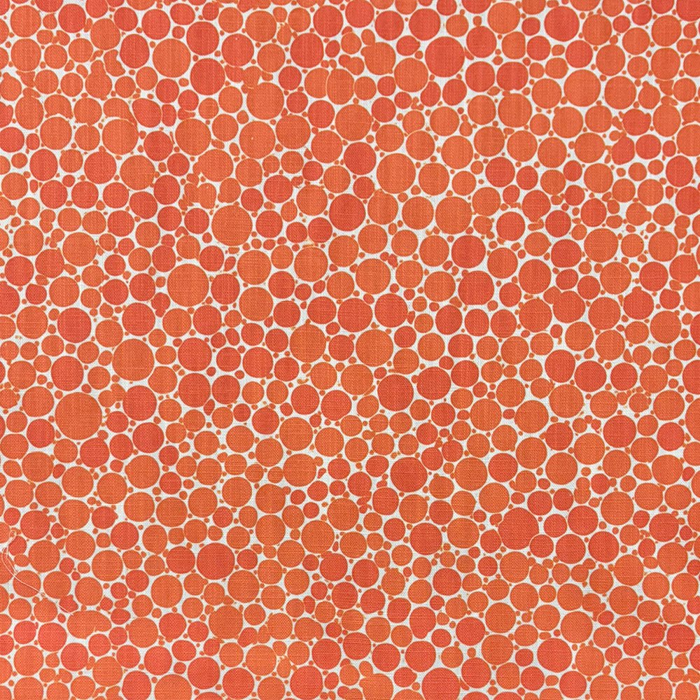 Close-up of Pointillia No.1 upholstery fabric featuring a vibrant orange dot pattern on a woven textile.